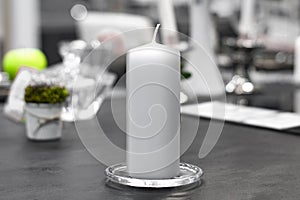 White candle on silver plate on served table.