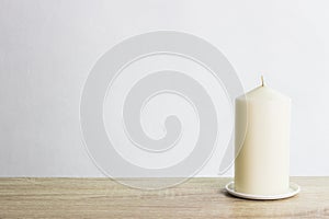 A white candle on a wooden table over the light background. photo