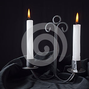 White candles in Gothic style holder on black velvet, black back