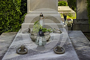 White candles and lanterns with greenery in the cemetery