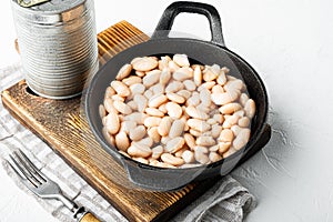 White canned beans, with metal can, in cast iron frying pan, on white stone  surface