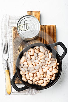 White canned kidney beans, with metal can, in cast iron frying pan, on white stone  surface, top view flat lay