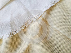 White canvas with fringe on a beige canvas close up. Bright fabric texture background