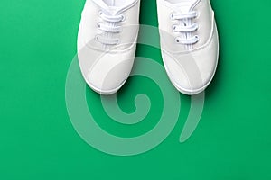 White canvas laced unisex shoes on green background. Classic casual sport footwear youth teenager urban fashion active lifestyle