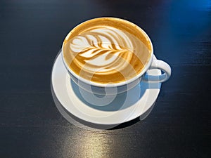 White cap of coffee latte on a black desk surface