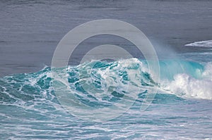 White capped aquamarine wave breaking.