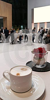 White cappuccino cup on saucer on table,business people on coffee break