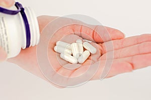 White capsule pills in a female hand close-up. Pills for unwanted pregnancy, oral contraception