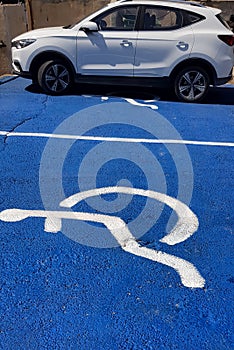 White car on blue painted asphalt of handicapped parking Distinct car area for disable people only