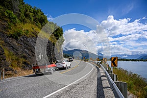 A white car with a boat Running on a curved road up the hill in the summer in wanaka lake