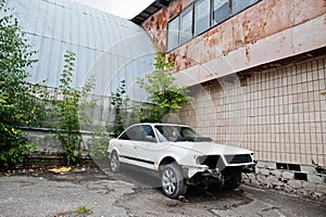 White car disassembled without headlights, bumper and egine at old factory