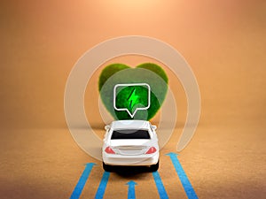 White car drive to green heart-shape with electric power icon, alternative energy, brown kraft paper background.