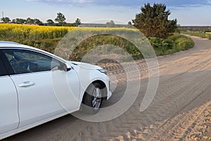 white car drives along a country road among a flowering rapeseed field. forward to adventure