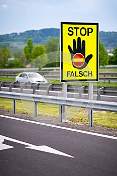 White car on the highway in the austrian countryside with the STOP/ FALSCH stop / false sign to warn the drivers