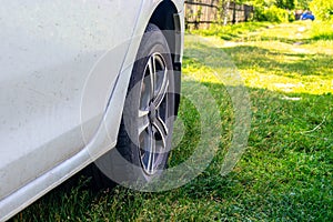 A white car is parked on the grass in the village. Close-up