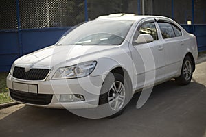 White car in parking lot. Car is parked on street. Personal transport in city