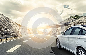 A white car rushing along a high-speed highway in the sun.