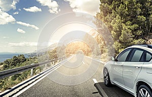 A white car rushing along a high-speed highway in the sun.