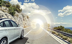 A white car rushing along a high-speed highway in the sun.