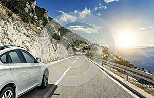 A white car rushing along a high-speed highway in the sun.