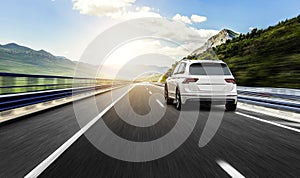 A white car rushing along a high-speed highway in the sun.