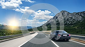 A white car rushing along a high-speed highway in the sun.