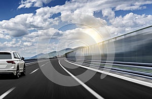 A white car rushing along a high-speed highway in the sun.