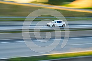 White car speeding in motion on a highway on a sunny day