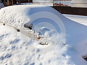 White car under snowdrift in parking lot