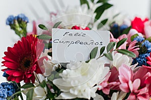 Card for a bouquet with the inscription happy birthday in spanish Feliz Cumplea os in a bright beautiful bouquet of flowers photo