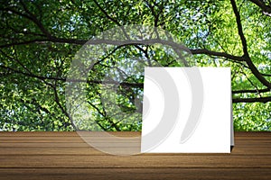 White card put on wooden desk or wooden floor on blurred green tree nature background.use for present or mock up your product