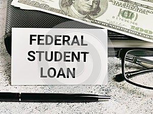 White card with text federal student loan with a pen and fake money.