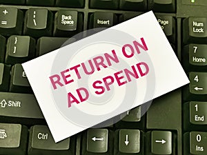 White card with text return on ad spend on computer keyboard.