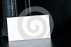 White card for writing with black leather bag on the table