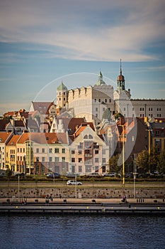 White castle with towers and green roofs and red roofs of residential and office houses and river in Szczecin, Poland