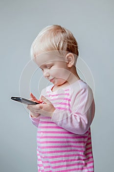 White Caucasian blond baby with blue eyes making a call, playing with mobile cell phone