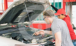 White caucasian car owner looking at main auto car engine after filling high energy power fuel in auto car tank in petrol station