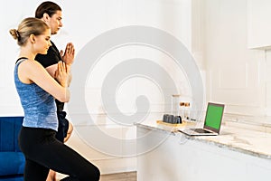 White caucasian couple do tree pose yoga at home