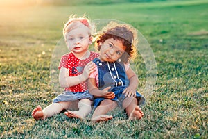 White Caucasian and latin hispanic babies hugging outside in park.