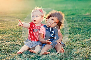 White Caucasian and latin hispanic babies hugging outside in park.