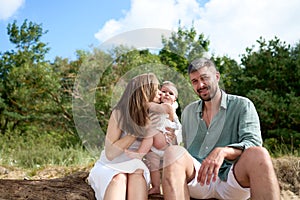 White Caucasian parents kissing their baby girl. Baltic sea, Latvia