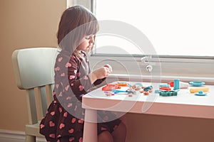 White Caucasian preschooler girl playing plasticine playdough indoors at home
