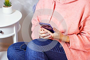 White Caucasian woman holding in her hand and using mobile phone app at home.