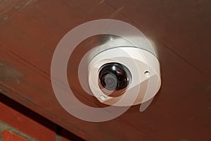 white CCTV surveillance camera mounted on ceiling of building