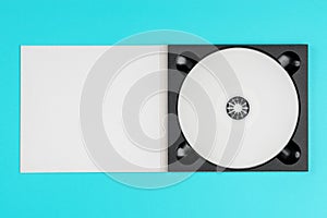 White cd in black case on pastel green background.