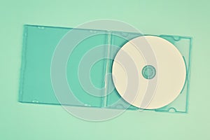 White cd in transparent case on pastel green background.