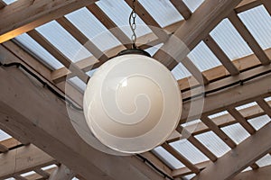 A white ceiling ball lamp hanging at outdoor patio, daytime