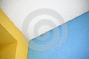 White ceiling edge with colorful blue and yellow walls, coated with roughcast