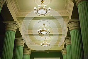 White ceiling with large chandeliers and green columns of classical style