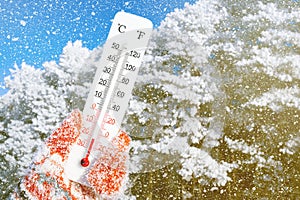 White celsius and fahrenheit scale thermometer in hand